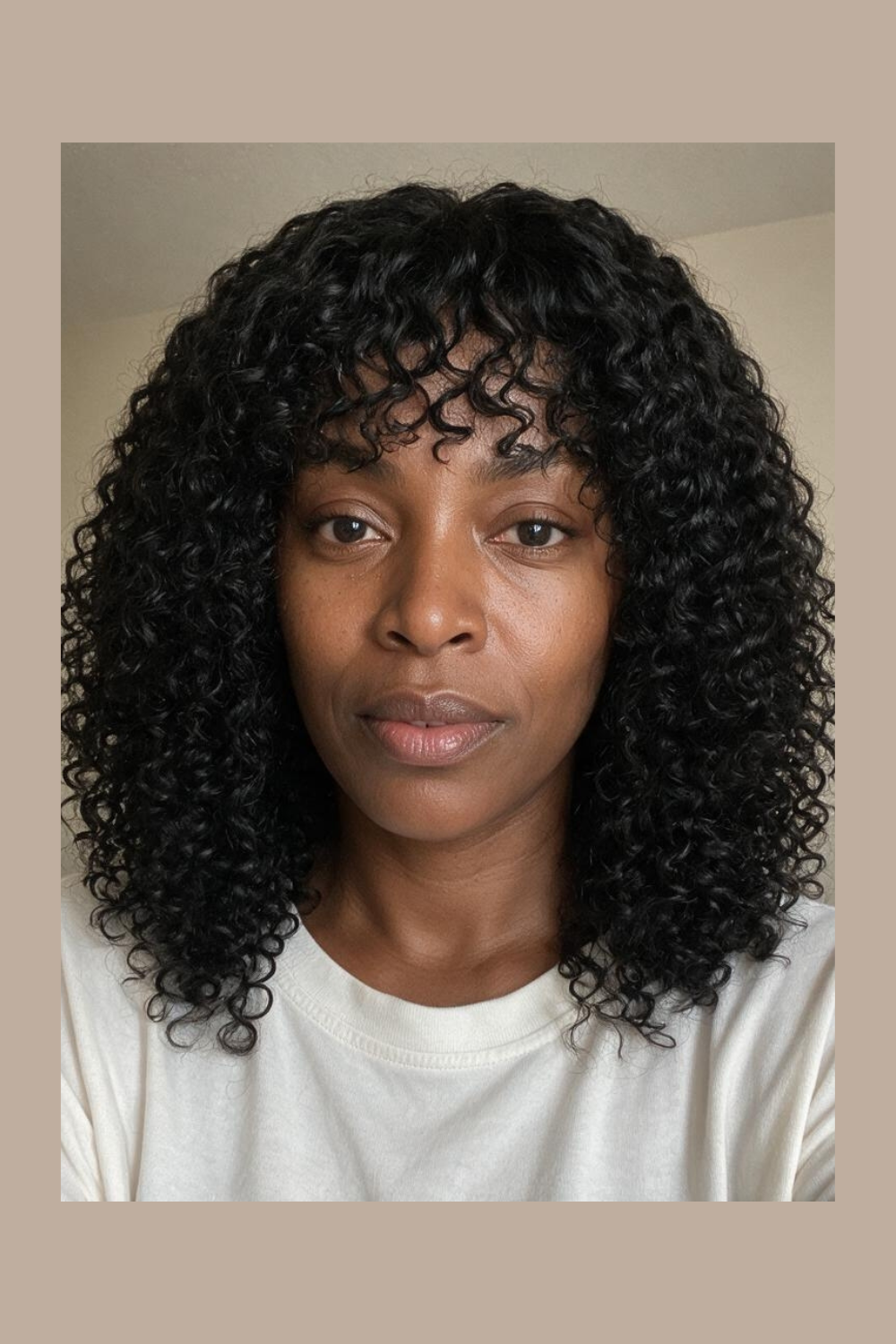Front view of a curly human hair wig with a fringe, cut to collarbone length